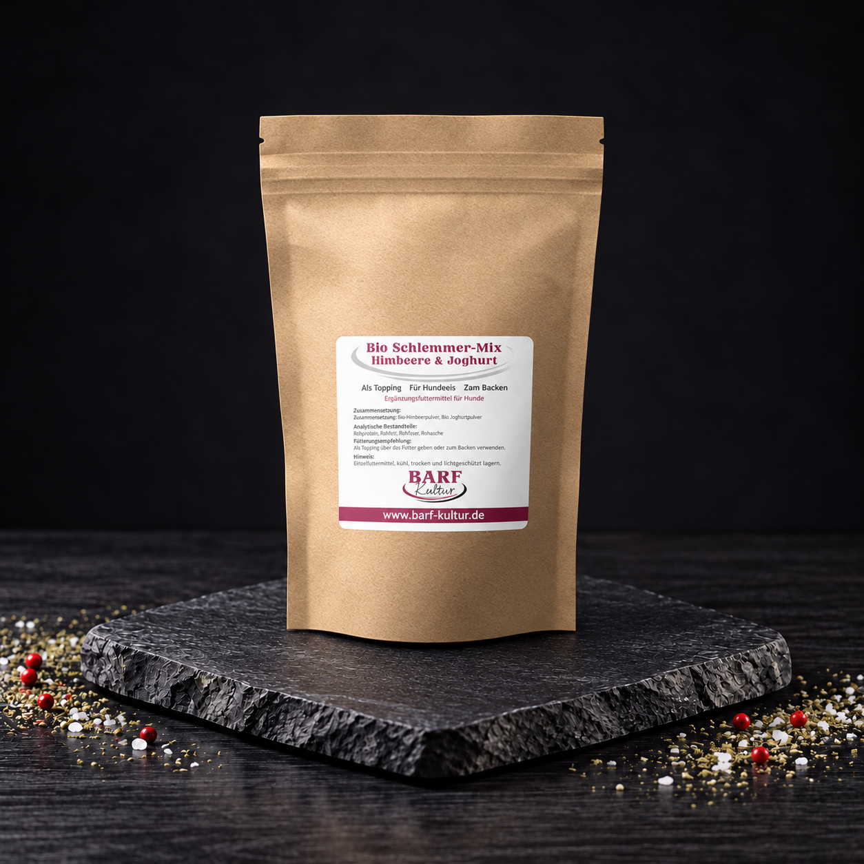 Bio Schlemmer-Mix Himbeere & Joghurt – dunkle Produktansicht Kraftpapierbeutel Bio Schlemmer-Mix Himbeere & Joghurt von BARF Kultur auf dunkler Steinplatte vor schwarzem Hintergrund